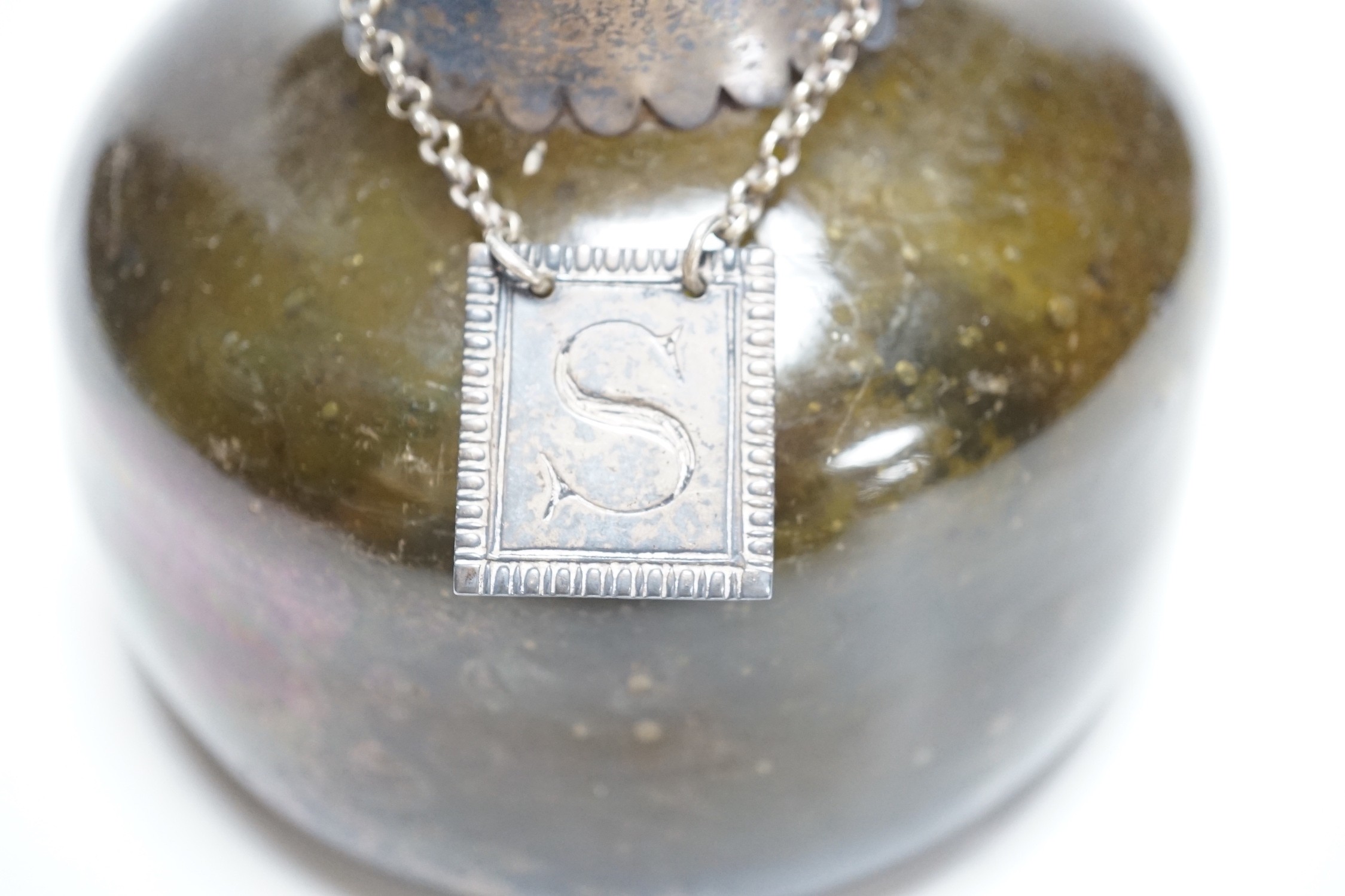 An 18th century green glass onion-shape bottle, with later silver mount, London, 1899, together with a George III silver 'S' decanter label, Phipps & Robinson, London, 1806. 17cm
